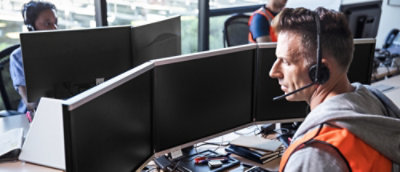 A person wearing a headset looking at a computer screen.