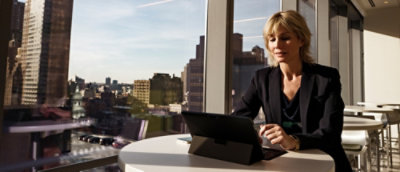 A woman looking at a laptop with hands typing on the keyboard.