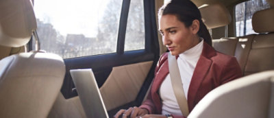 A person sitting in a car using a laptop.