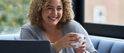 A close-up of a woman holding a cup while smiling.