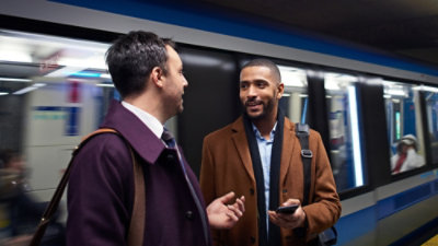 A group of people standing in a subway with one person holding a phone.
