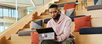 A man sitting on a staircase looking at a tablet.