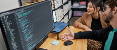 A man and woman sitting at a table with a laptop.