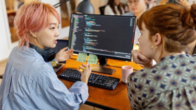 A group of people sitting at a desk looking at a computer screen.