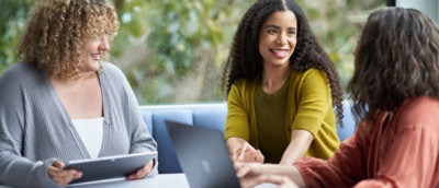 Three women collaborating at a table with a laptop.