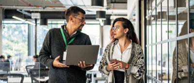 A man and woman holding a laptop and talking.