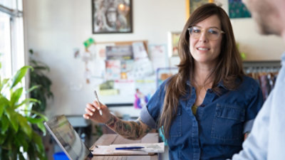 A woman smiling while holding a tablet pen.