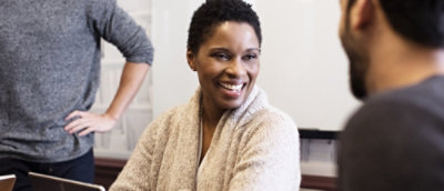 A woman smiling having a tablet infornt.