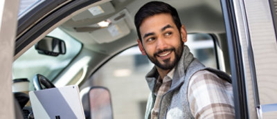A person wearing a plaid shirt smiling in a car.