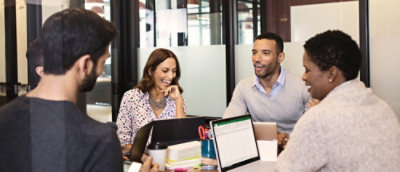 A group of people sitting around a table with a laptop visible.