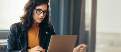 A person wearing glasses and looking at laptop screen.