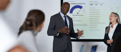 A man in a suit standing in front of a projection screen.