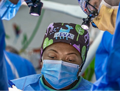 A person wearing a surgical mask and scrubs with the text EVA visible.