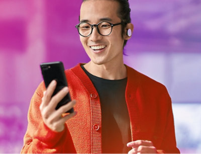 A man wearing glasses and a red cardigan holding a phone.