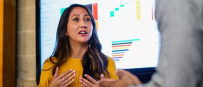 A person in a yellow shirt holding a pen with their hands in front of their chest.