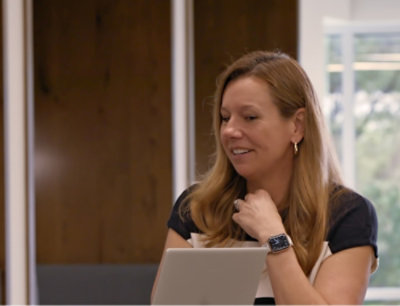 A woman smiling while using a laptop.