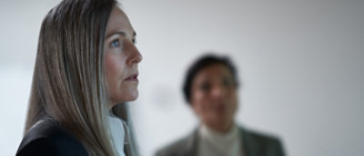 A professional woman and a man in suits stand confidently together.