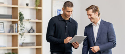 Two people smiling while looking at a tab.