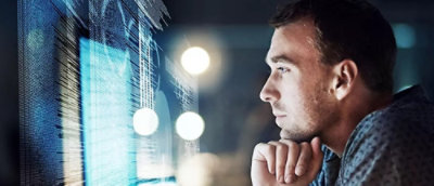 Person in front of a computer screen displaying code.