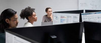 Group of people viewing charts and data on computer monitors.