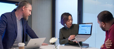 Three people in office viewing graph on laptop.