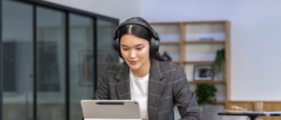 A women wearing headphones and looking at the laptop.