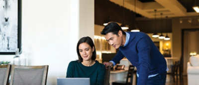 Two people in modern room viewing laptop together