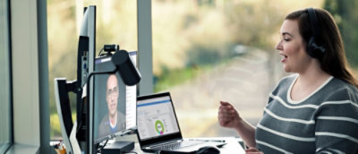 Person on video call at desk with laptop and monitor.