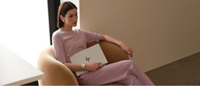 A person sitting in a chair holding a laptop.