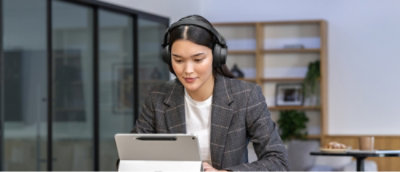 A person wearing headphones and looking at a laptop.
