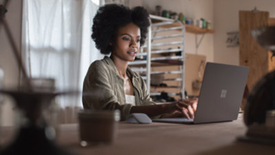 Osoba, která sedí u stolu a dívá se na obrazovku přenosného počítače.