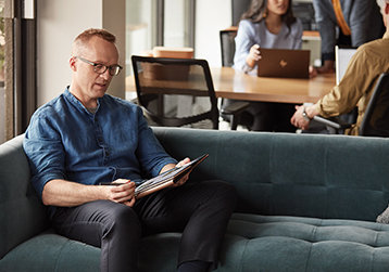 A person sitting on a couch working on a tablet