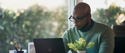 A person wearing glasses looking at a laptop.