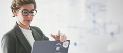 A person in a suit holding and looking at a laptop.