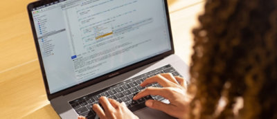 A hand typing on a laptop keyboard.
