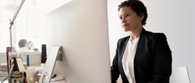 A woman in a suit looking at a computer screen.