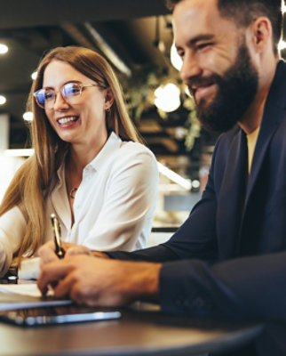 一名穿着白 T 恤戴眼镜的女士对着一名男士微笑。