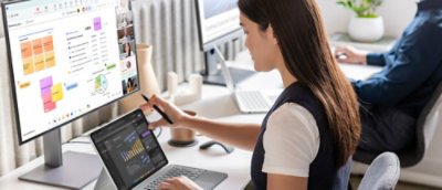 Woman working on data analysis using dual screens in a modern office setup.