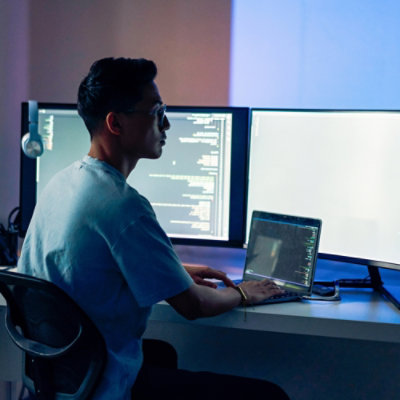 Seorang pria duduk di kursi dan bekerja di depan komputer