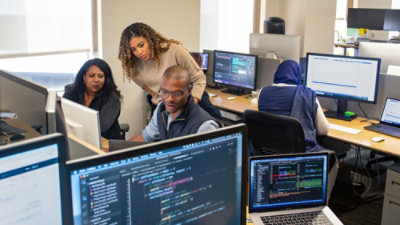 Drie personen op kantoor kijken naar een desktop