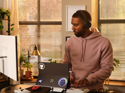 Een man met een hoofdtelefoon die achter een laptop werkt.