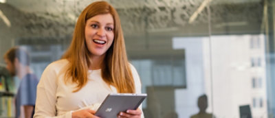 A woman looking at the tablet and smiling