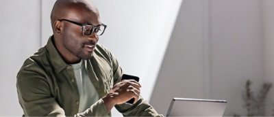 A man holding a coffee cup and looking at laptop screen.
