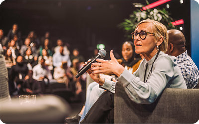 Một người phụ nữ ngồi trên ghế và đang cầm micrô.