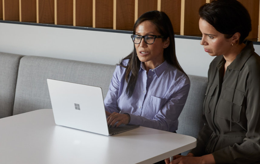 Two people look over a Surface Laptop 3 device.