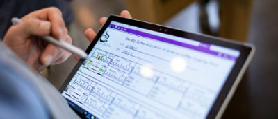 บุคคลที่ใช้ปากกาแท็บเล็ตกับแท็บเล็ตที่แสดงแผนภูมิและการวิเคราะห์บนแดชบอร์ดการเงิน