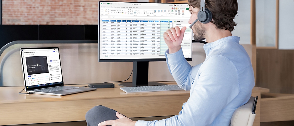 Un hombre con auriculares sentado en un escritorio trabaja en un equipo con datos en una hoja de cálculo en la pantalla en una oficina moderna 