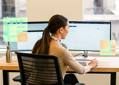 A woman sitting at a table using a desktop.