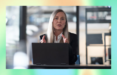 A women seating infront of laptop explaining something in a meeting room
