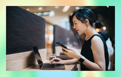 A women holding a mobile and working in laptop.